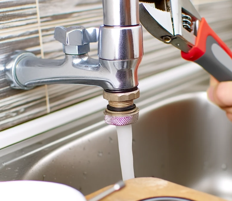 Man fixing a leaking faucet with wrench and new washer